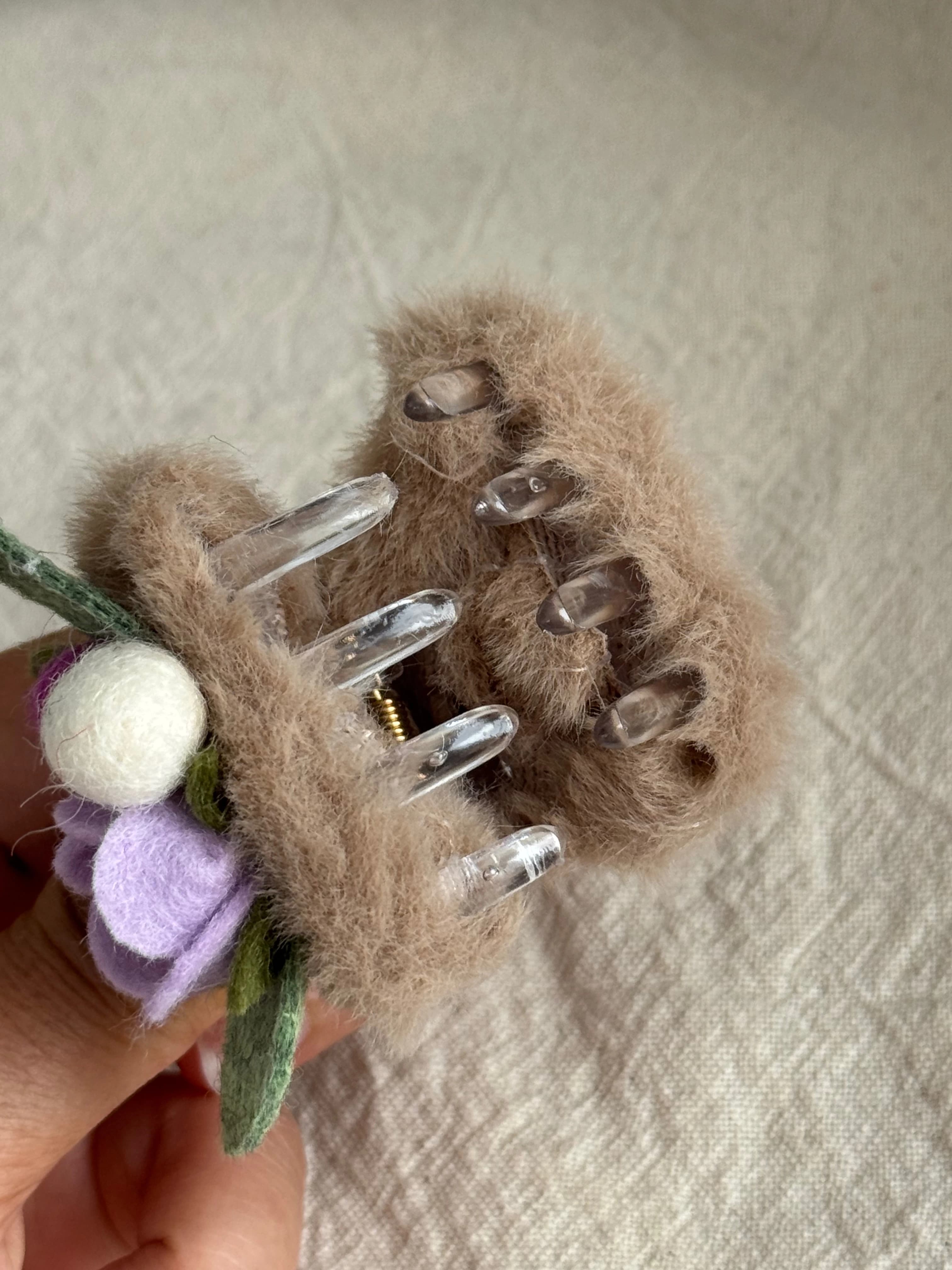 Claw fastening beneath the taupe and purple rose cat-ear clip
