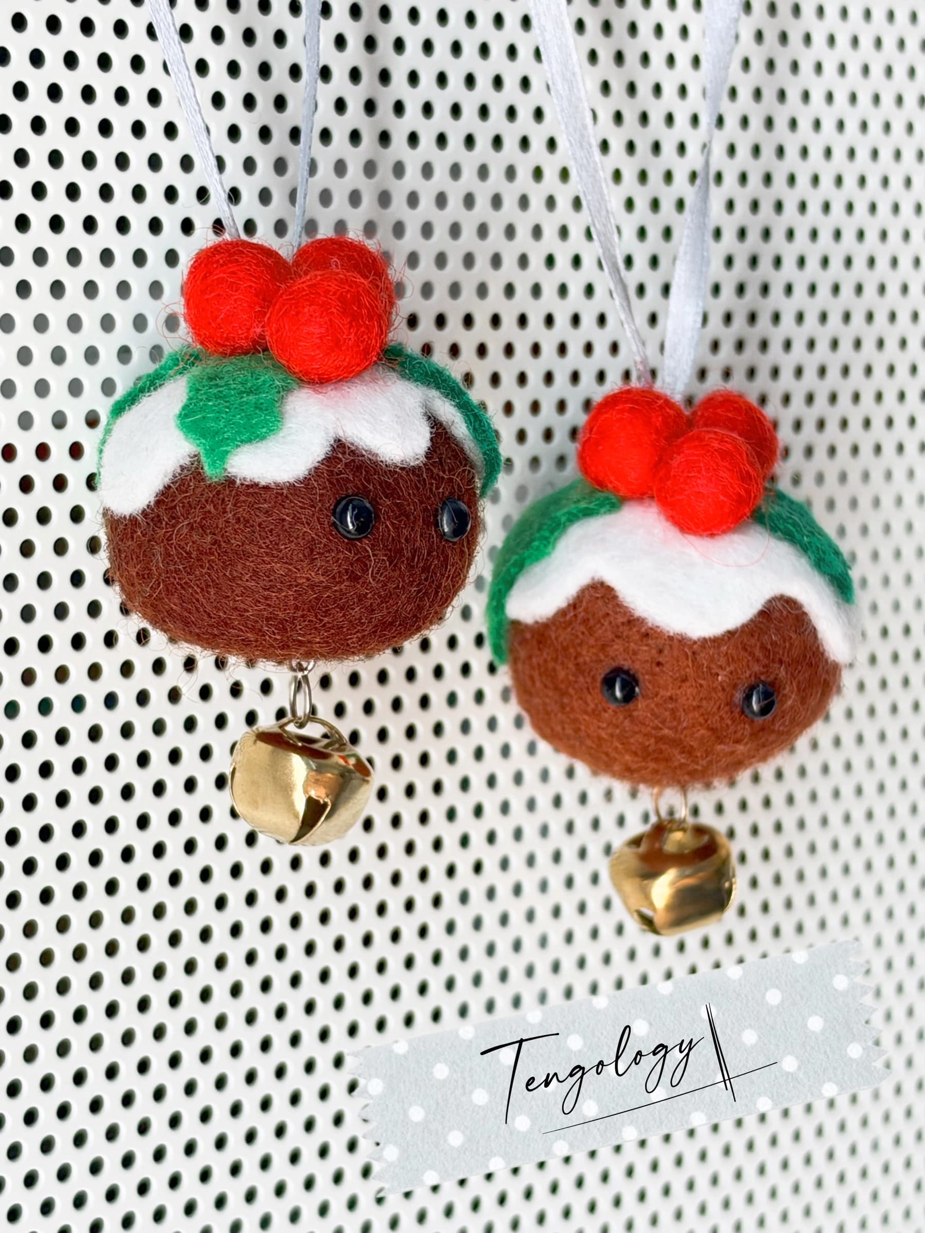 A pair of felt Christmas pudding ornaments with custard tops, holly and red berries, hanging side by side