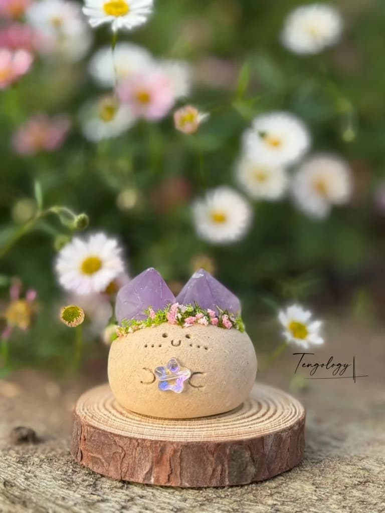 A Crysprout crowned with twin amethyst points and pink dried flowers