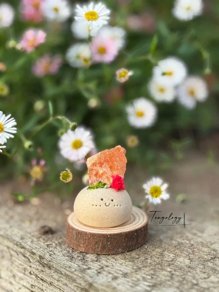 A small Crysprout with bright orange rough stone and a red dried flower