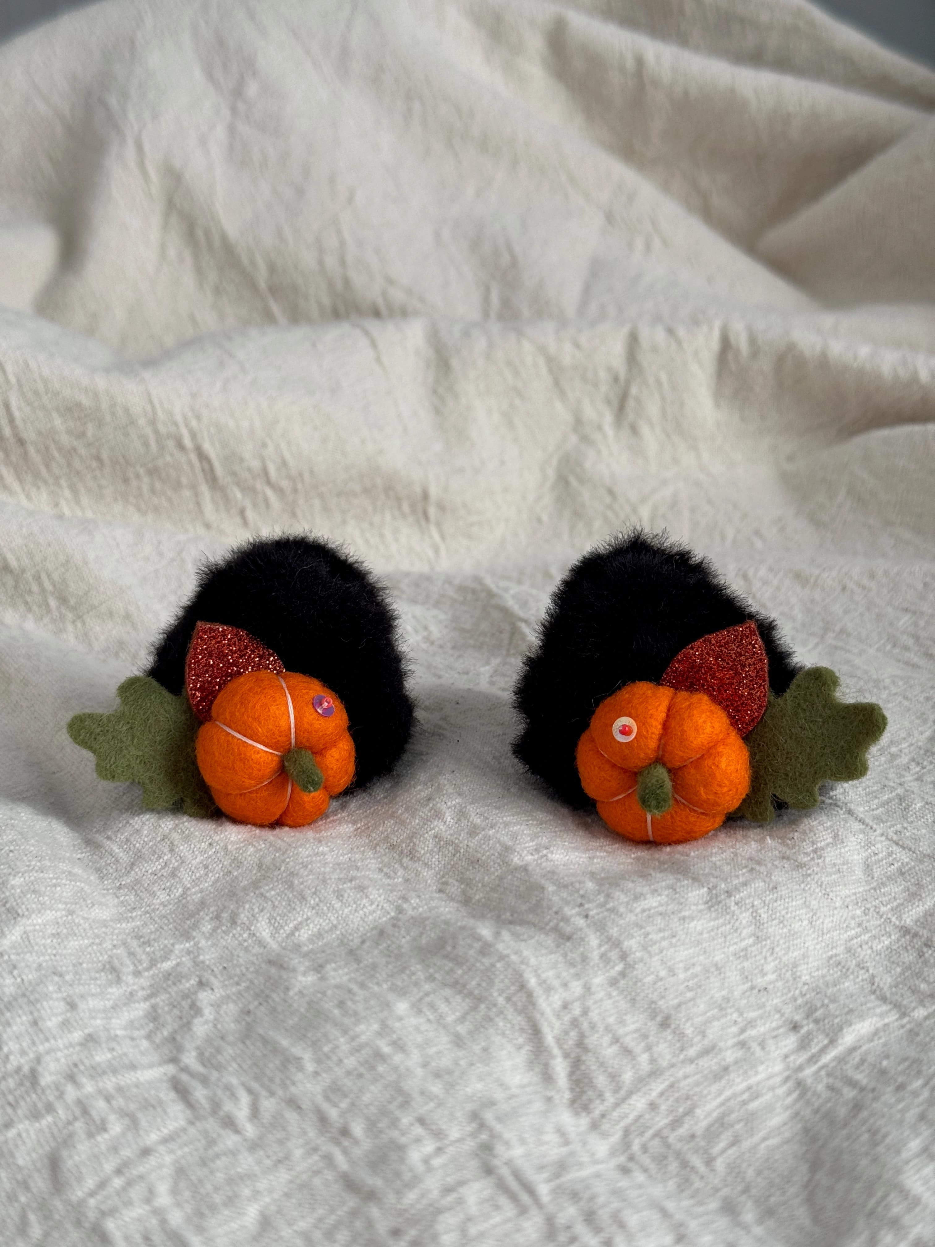 Pair of black faux-fur mini claw clips with orange felt pumpkins and autumn leaves