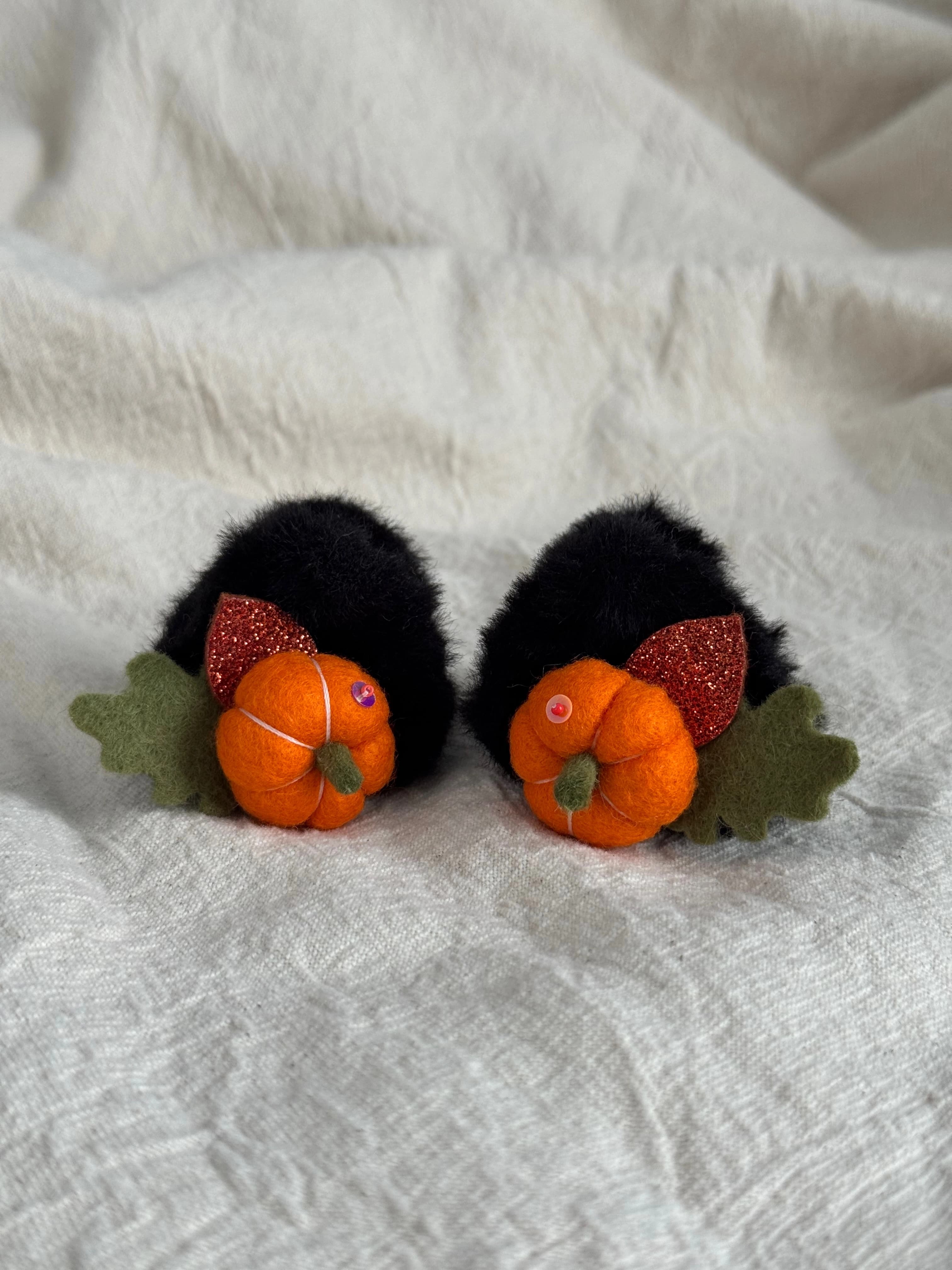 Pair of black faux-fur mini claw clips with orange felt pumpkins and autumn leaves