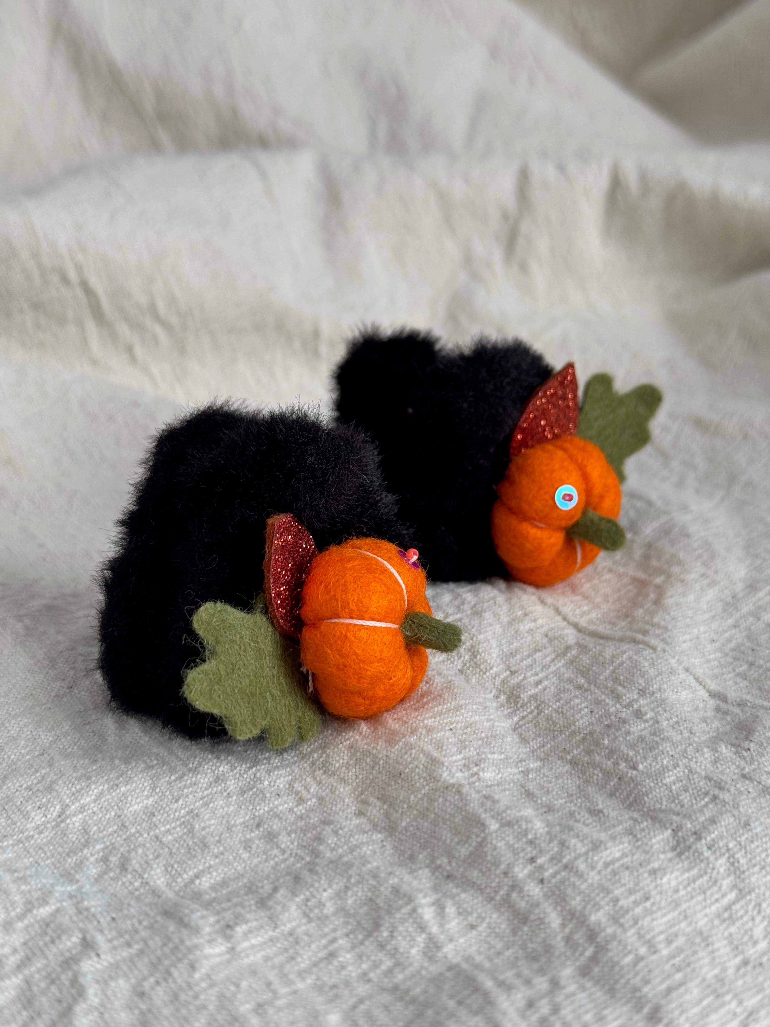 Pair of black faux-fur mini claw clips with orange felt pumpkins and autumn leaves