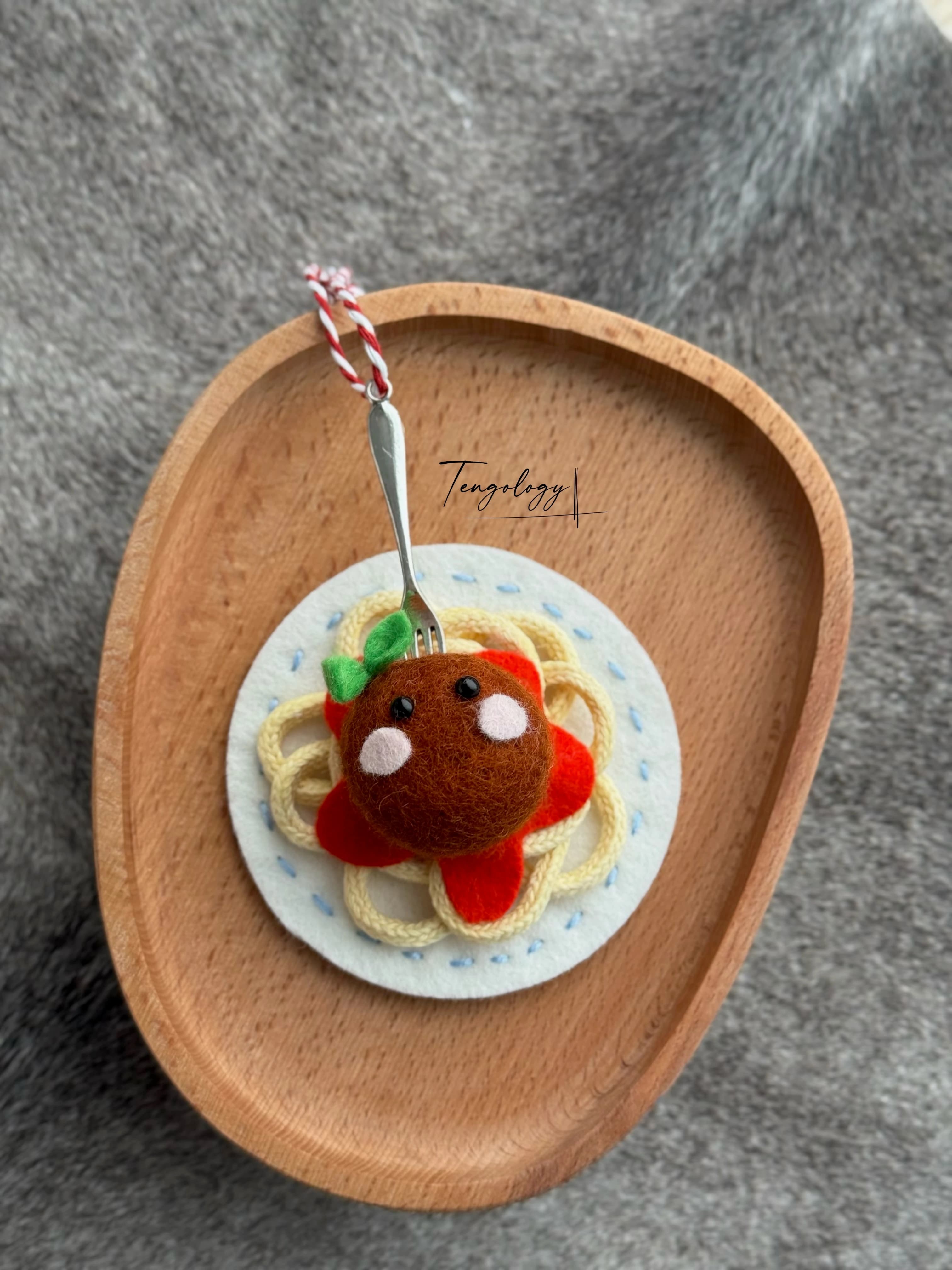 Spaghetti and meatball felt ornament with light blue stitching around the plate