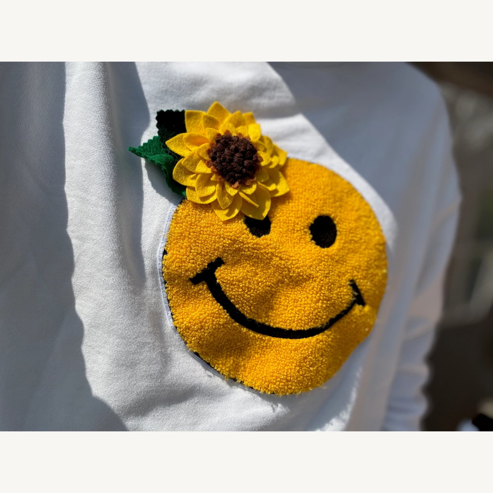 Sunflower felt brooch worn on a white top