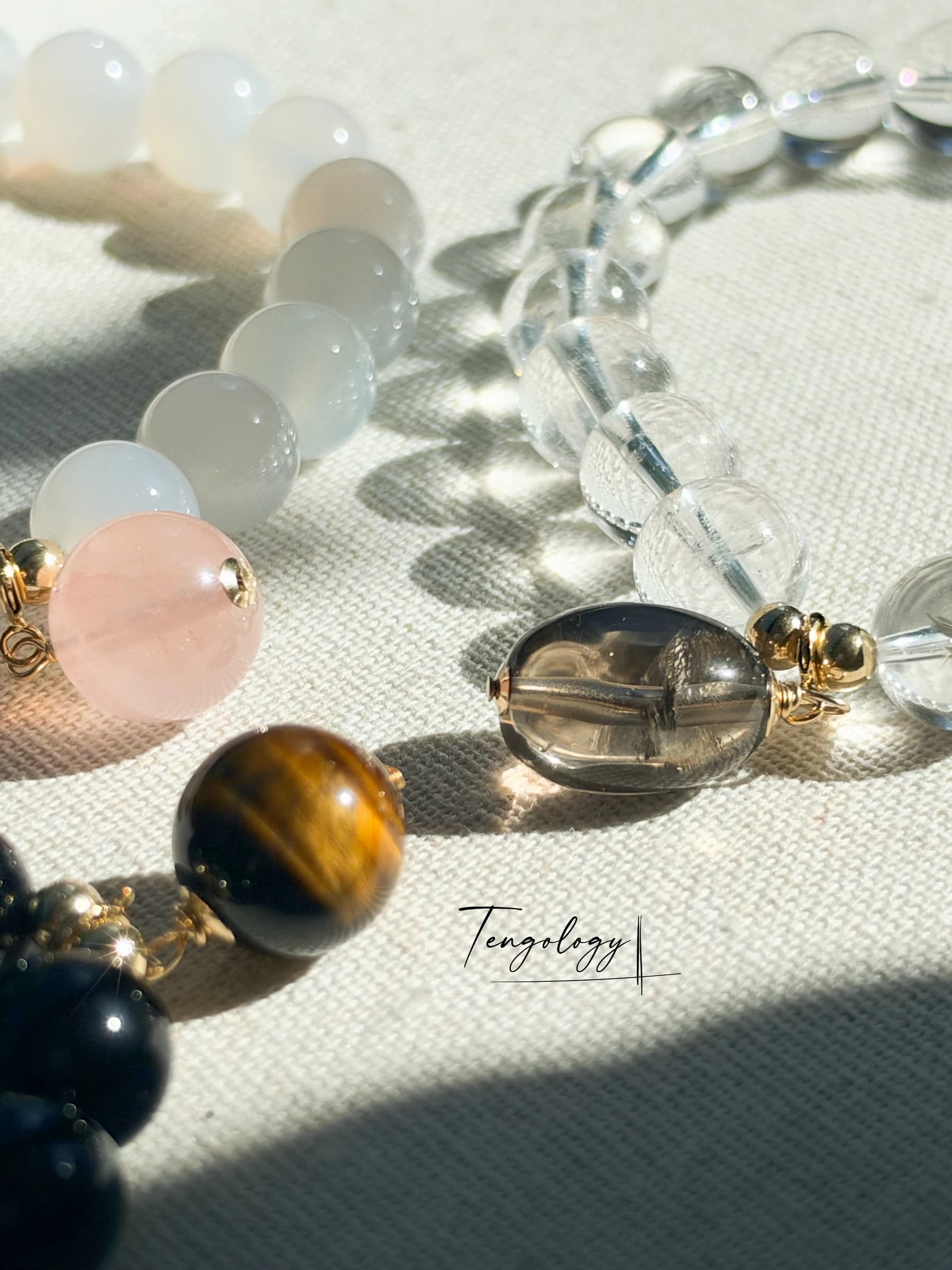 Orbit Starter Set bracelets and charms in sunlight, casting shadows on pale fabric